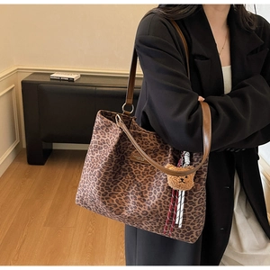 Dettaglio della borsa tote in tela leopardata con cinturini in pelle e ciondolo a orsetto