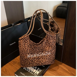 Detail of leopard print tote bag with brown straps placed on a decorative design book
