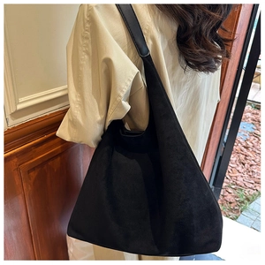 Close-up of black suede tote bag showing soft texture and sleek crescent design
