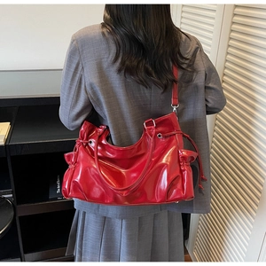 Détail d'un sac cabas en cuir verni rouge brillant avec cordons latéraux sur un mannequin