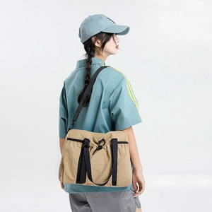 Detail view of khaki nylon travel bag with reinforced black strap and adjustable buckle