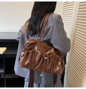 Détail de la vue arrière d'un grand sac vintage marron avec des poches plissées décoratives