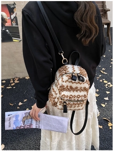 Outdoor-Look eines Mini-Plüschrucksacks aus brauner und weißer Lammwolle am Model