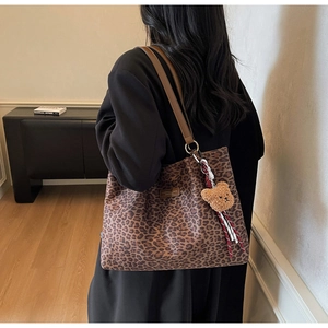 Dettaglio della borsa tote leopardata con cinturini in pelle marrone e ciondolo orso