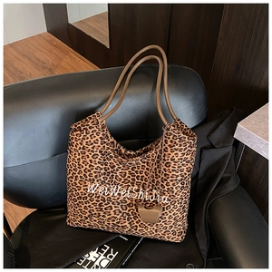 Detailed view of leopard print tote bag with brown handles on a leather chair