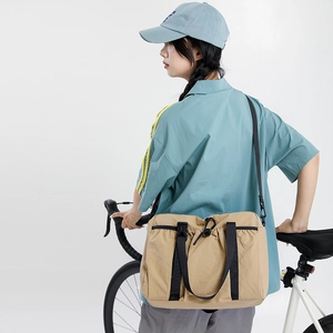 Detail of khaki nylon tote bag featuring drawstring closure and black webbing buckles