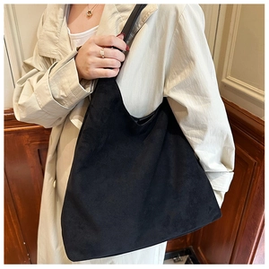 Black suede tote bag on model showing large capacity and soft matte texture detail