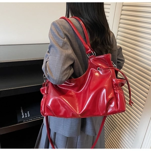 Sac cabas rouge brillant porté par un mannequin en tailleur gris pour un look chic