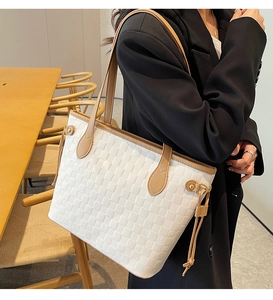 Detailed view of woven white tote bag with tan leather straps on model shoulder