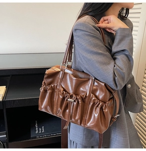 Détail d'un sac cabas plissé marron avec un blazer à carreaux gris et une bandoulière