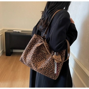 Dettaglio della borsa tote leopardata in tela con manici in pelle e ciondolo orsetto