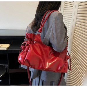 Vue détaillée du sac cabas en cuir verni rouge vif avec plis de serrage et effet brillant