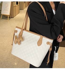 Detail of white woven tote bag with brown leather trim and a cute puppy charm