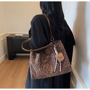 Dettaglio borsa tote leopardata grande con manici in pelle marrone e ciondolo orsetto