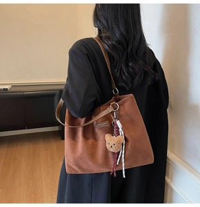 Brown suede tote bag detail with cute bear charm and woven tassel decoration