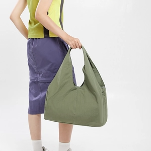 Detail view of large olive green nylon tote bag showing spacious capacity and pleated texture