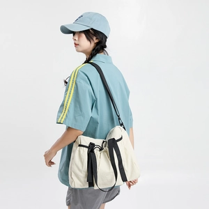 Detail view of cream travel tote featuring adjustable drawstring and black contrast straps