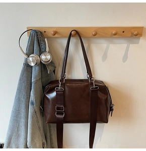 Grand sac fourre-tout marron foncé avec boucles argentées suspendu à un crochet en bois
