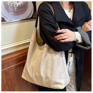Detail of beige suede tote bag with brown leather strap showing capacity and texture