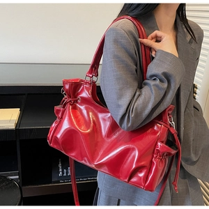 Détail du sac à bandoulière rouge brillant avec texture plissée et cordons latéraux
