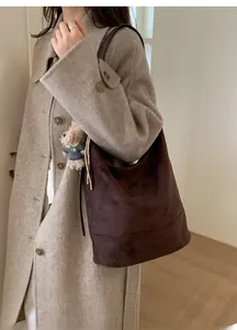 Detail of dark brown suede hobo bag with cute plush bear charm on grey wool coat