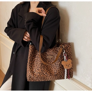 Dettaglio della borsa tote leopardata con manici in pelle marrone e ciondolo orsetto