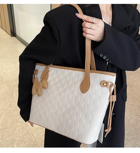 Detail of cream woven tote bag with brown leather trim and cute puppy charm on handle