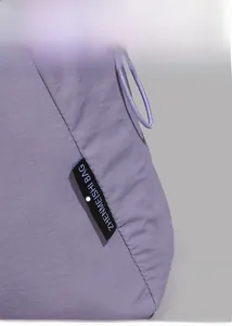 Detail of light purple nylon tote bag with black fabric label and drawstring decor