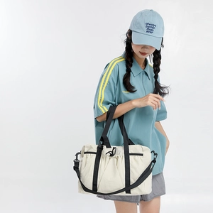 Close-up of minimalist cream nylon tote bag with black straps and pleated details