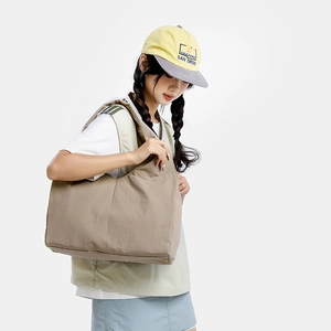 Detail shot of khaki nylon tote bag with wide strap on model in casual style
