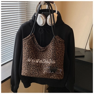 Detailed close-up of brown leopard print tote bag with white embroidery on casual hoodie