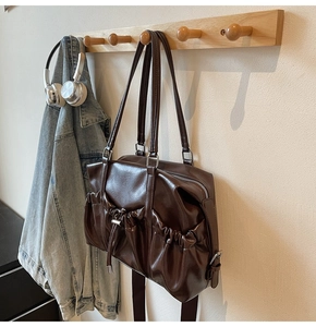 Détail d'un sac cabas vintage marron foncé suspendu avec des objets du quotidien