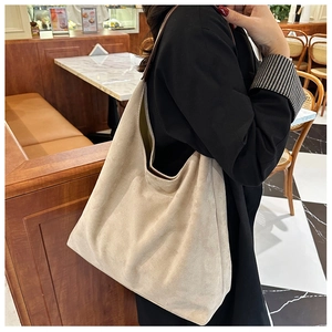 Detail of a beige suede tote bag with brown straps shown in a cozy cafe setting