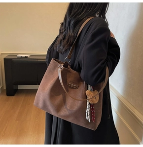 Detail of vintage brown suede tote bag with leather tag, plush bear charm and silk scarf