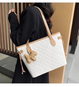 Detail of white woven tote bag with brown trim and cute puppy charm on the side