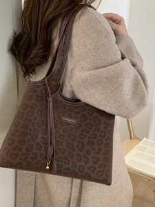 Brown leopard print tote bag with gold nameplate shown in a cozy lifestyle setting