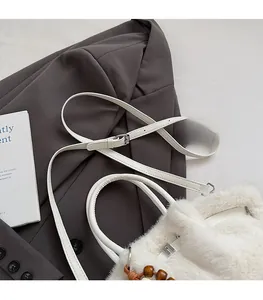 Detail der weißen Plüschtasche mit verstellbarem Lederriemen und dekorativen Holzperlen