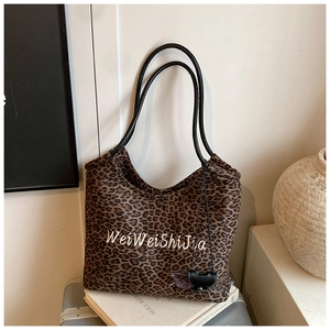 Detail of leopard print tote bag with white embroidery and black slim shoulder straps