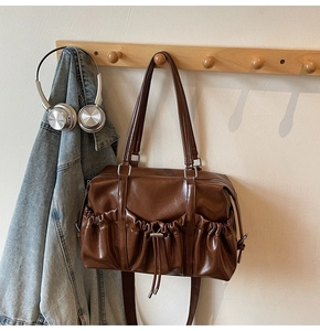 Close-up of dark brown shiny PU leather bag with pleated drawstring and silver hardware