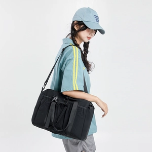 Close-up of black nylon travel tote with drawstring pockets and adjustable shoulder strap