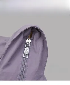 Detail of silver metal zipper with embossed logo on a purple fabric tote bag