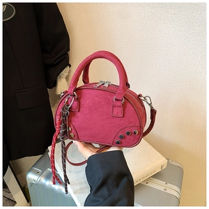 Détail du sac bowling en cuir mat bordeaux avec clous métalliques et pendentif