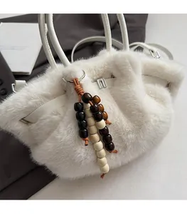 Detailansicht der weißen Pelz-Handtasche mit modischem Holzperlen-Anhänger und weichem Plüsch