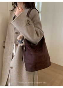 Detail of vintage suede tote bag in dark coffee with a cute bear pendant on a wide strap