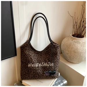 Detail of leopard print tote bag with embroidery on silver suitcase and decor