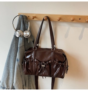 Close-up of retro pleated texture and metal drawstring pocket on dark brown tote bag