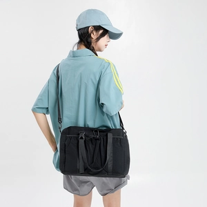 Detail of black nylon travel tote featuring drawstring pockets and adjustable straps