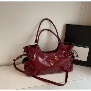 Détails d'un sac cabas en cuir brillant rouge foncé avec plis et garnitures argentées