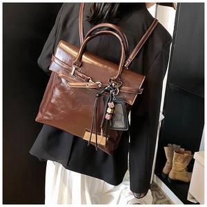 Détail du sac à dos en cuir marron poli avec boucle métallique et breloque perlée