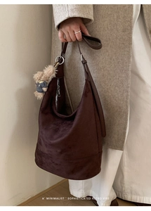 Detail of dark brown suede hobo bag with teddy charm on a beige coat outfit